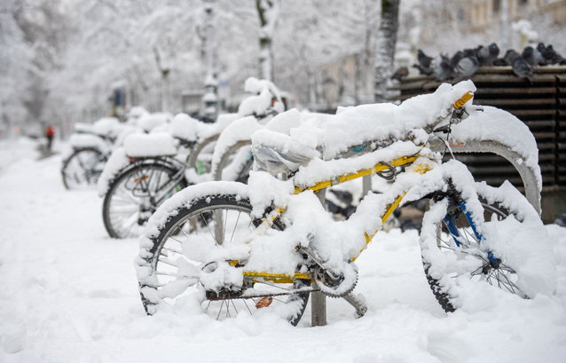 (Dieser ALT-Text wurde mithilfe von KI erstellt) Mehrere Fahrräder stehen an einem Fahrradständer im Freien und sind vollständig mit Schnee bedeckt.
