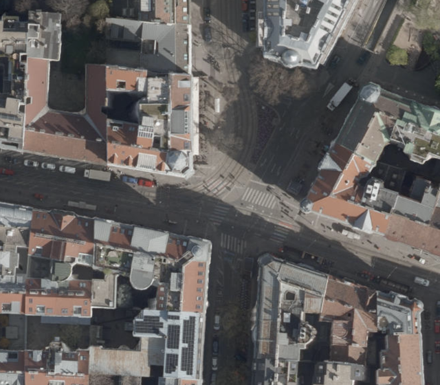 (Dieser ALT-Text wurde mithilfe von KI erstellt) Luftbild einer städtischen Kreuzung mit umliegenden Gebäuden und Straßen, aufgenommen bei Tageslicht.