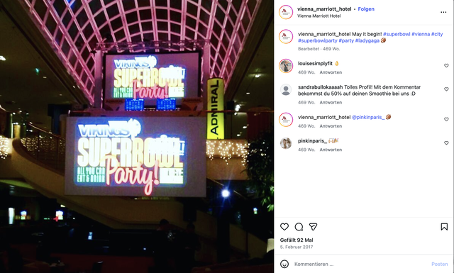(Dieser ALT-Text wurde mithilfe von KI erstellt) Zwei große Leinwände im Vienna Marriott Hotel zeigen Werbung für eine „Superbowl Party“ mit dem Hinweis „All you can eat & drink“.