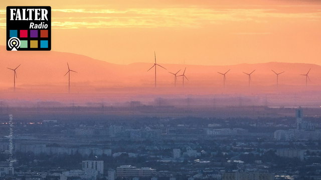 (Dieser ALT-Text wurde mithilfe von KI erstellt) Blick über eine Stadt im Vordergrund mit mehreren Windrädern im Hintergrund bei Sonnenuntergang; oben links das Logo von Falter Radio.