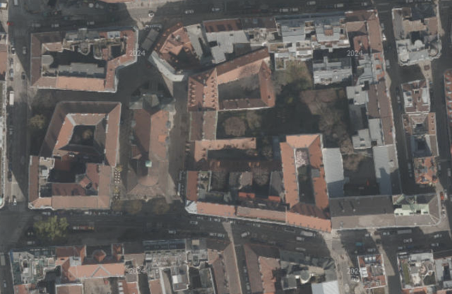 (Dieser ALT-Text wurde mithilfe von KI erstellt) Satellitenbild zeigt mehrere Wohngebäude mit Innenhöfen und Straßen in einem städtischen Viertel aus der Vogelperspektive.