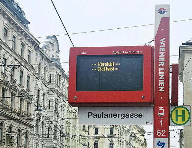 (Dieser ALT-Text wurde mithilfe von KI erstellt) Digitale Anzeigetafel an der Haltestelle Paulanergasse der Wiener Linien mit Warnhinweis „Vorsicht Glatteis!“.
